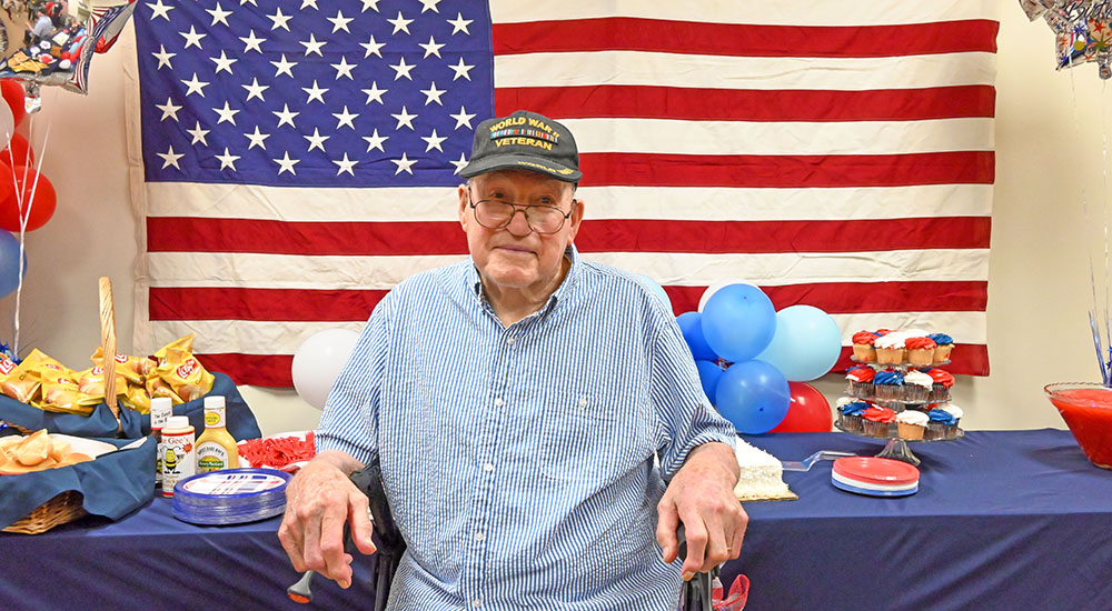 100 year old Veteran with American flag and party table
