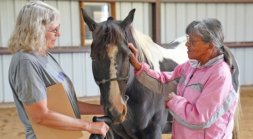 Woman helps woman approach horse as part of Healing with Horses program