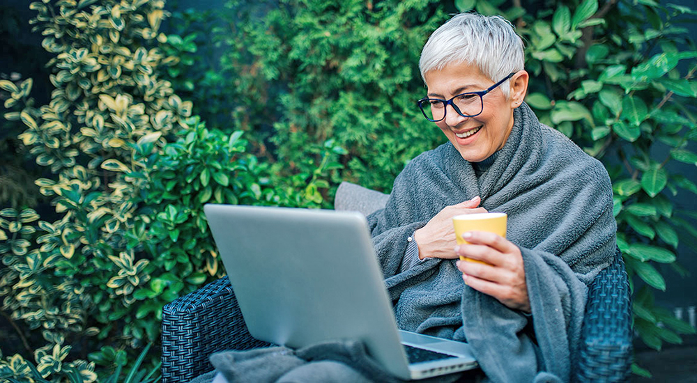 Woman outside receiving virtual caregiver peer support on her laptop