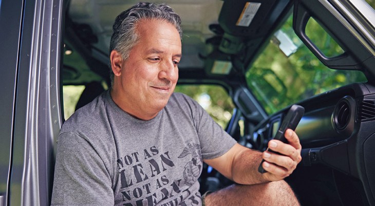 Man reading kidney information on a phone in his truck