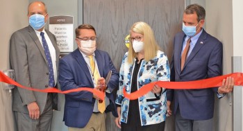 Four people cut ribbon at new clinic