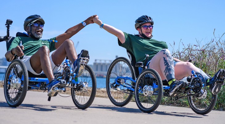 Two Veterans holding hands in special racing bikes at Summer Sports Clinic