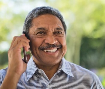A man smiles while speaking on the phone to a member of his caregiver support team