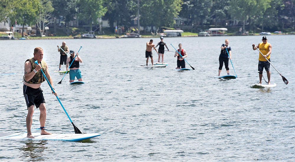 Nine Veterans paddleboarding on a lake