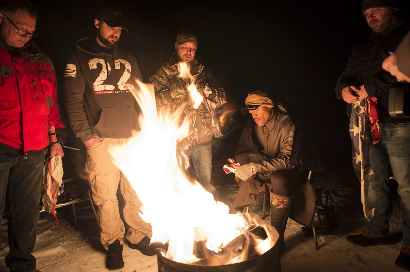 men huddled around a bonfire