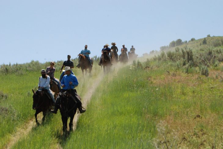 People riding horses over a hilltop during a retreat