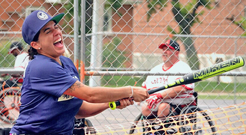 Woman in wheelchair swinging bat in softball game