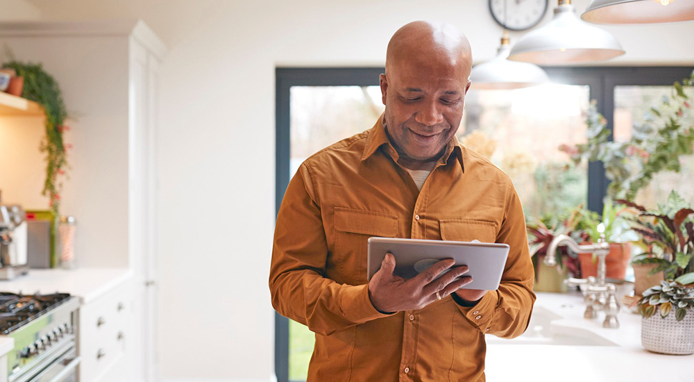 Man using telehealth from his tablet in his kitchen to access care