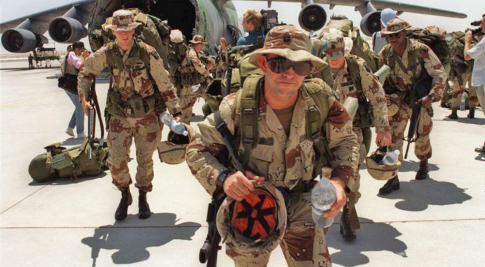 Gulf War Soldiers with gear leaving large aircraft