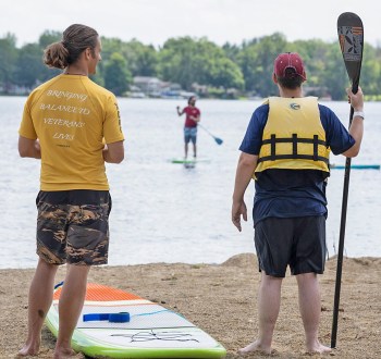 Two paddle board instructors on a beach