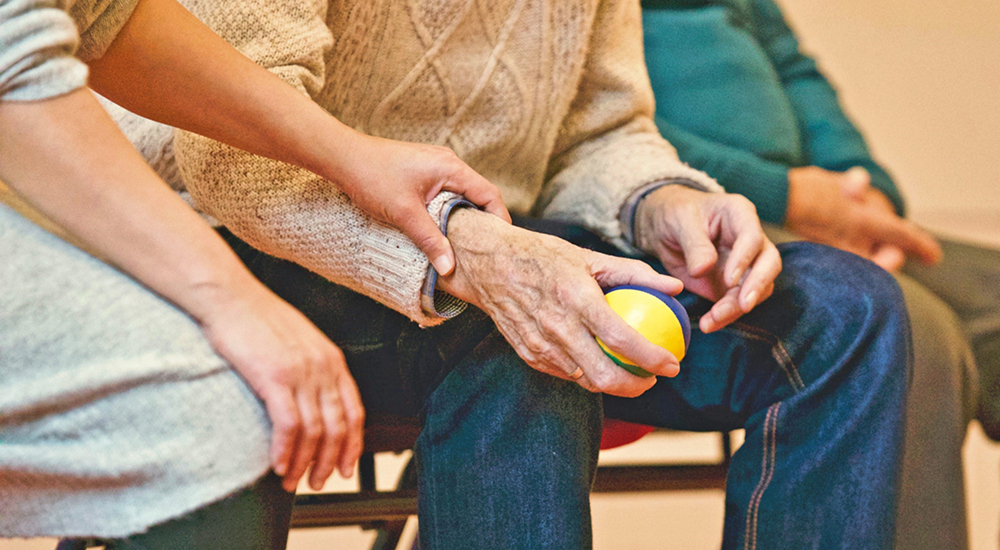 Someone holding the arm of an elderly man; palliative care