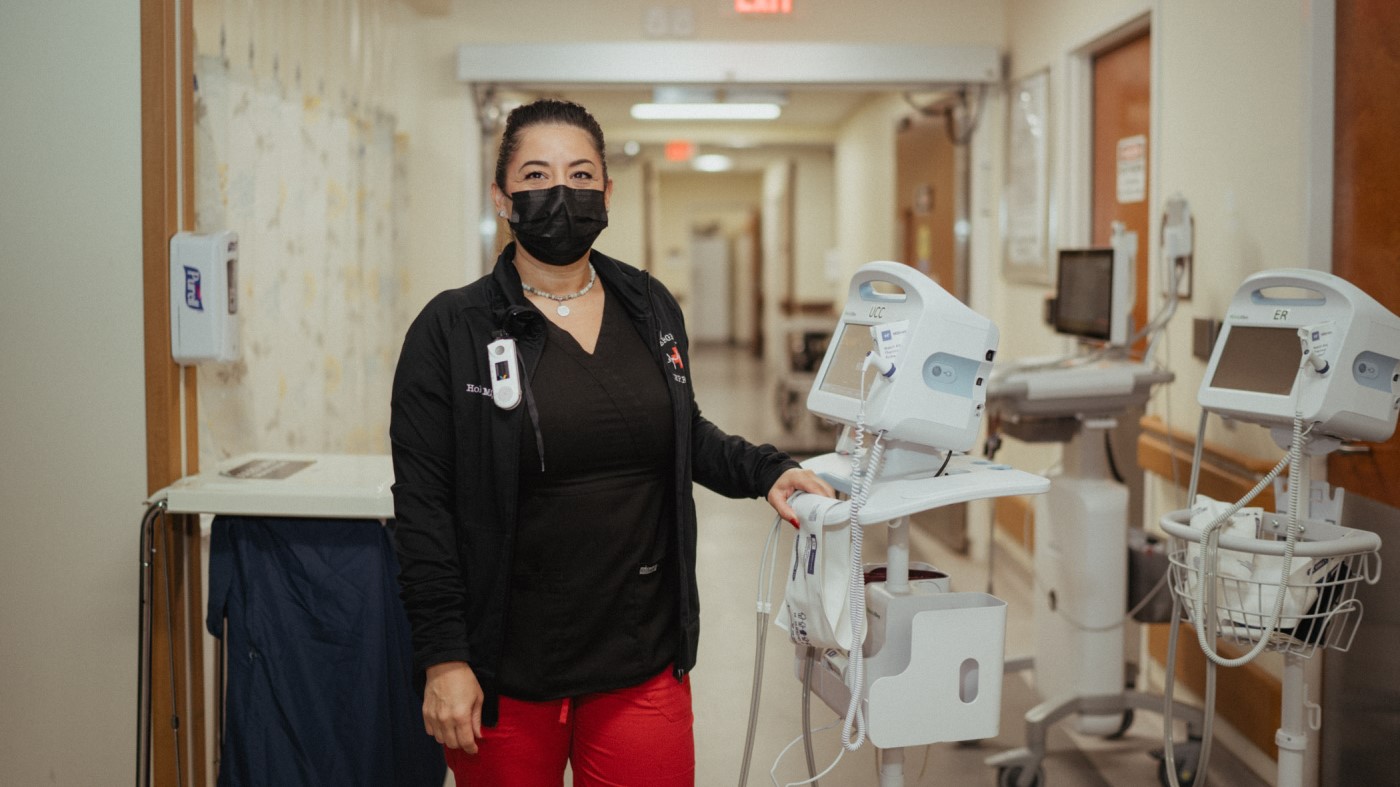 A nurse in a medical center hallway, prepping equipment.