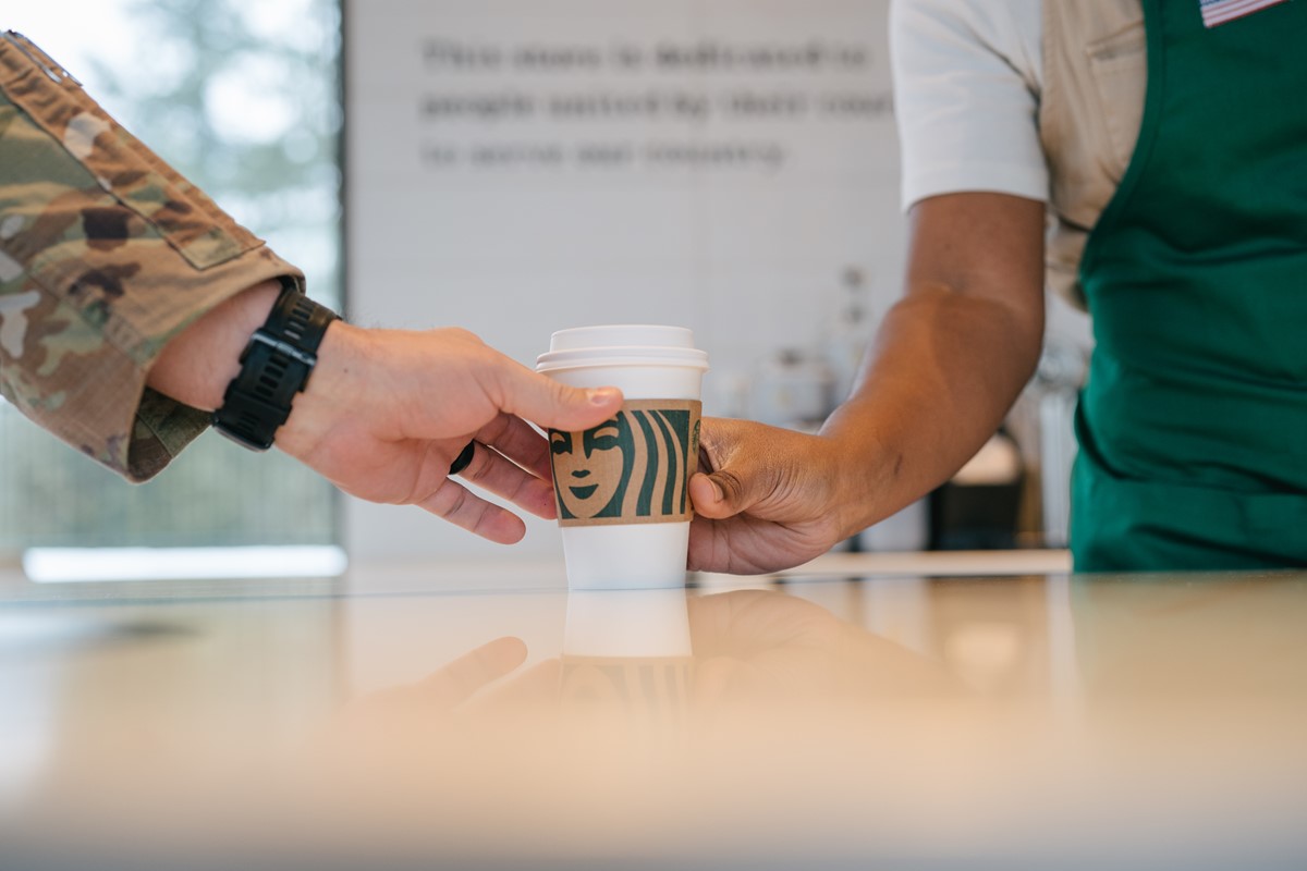 barista handing coffee to a person in uniform