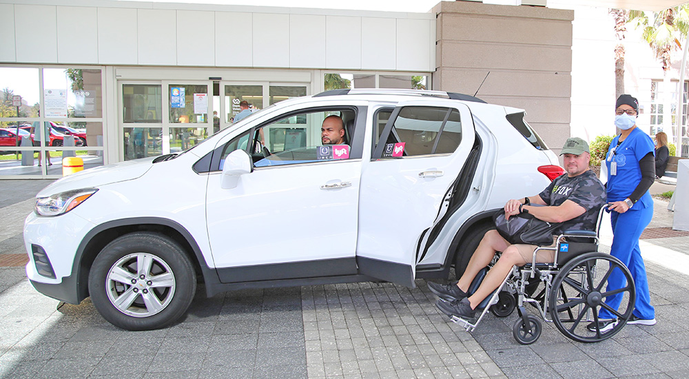 Nurse pushing Veteran in wheelchair to automobile for rideshare