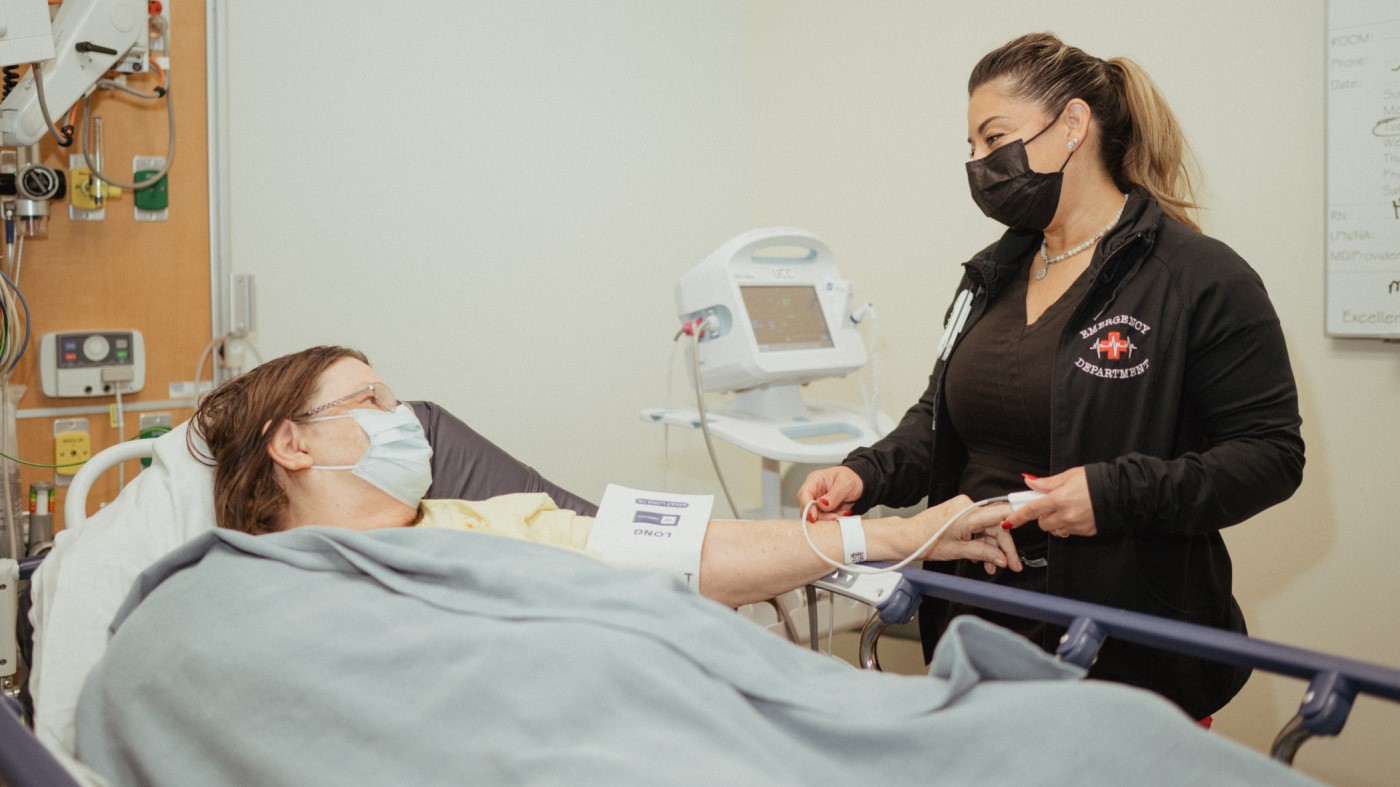 A VA nurse holds a patient’s hand.