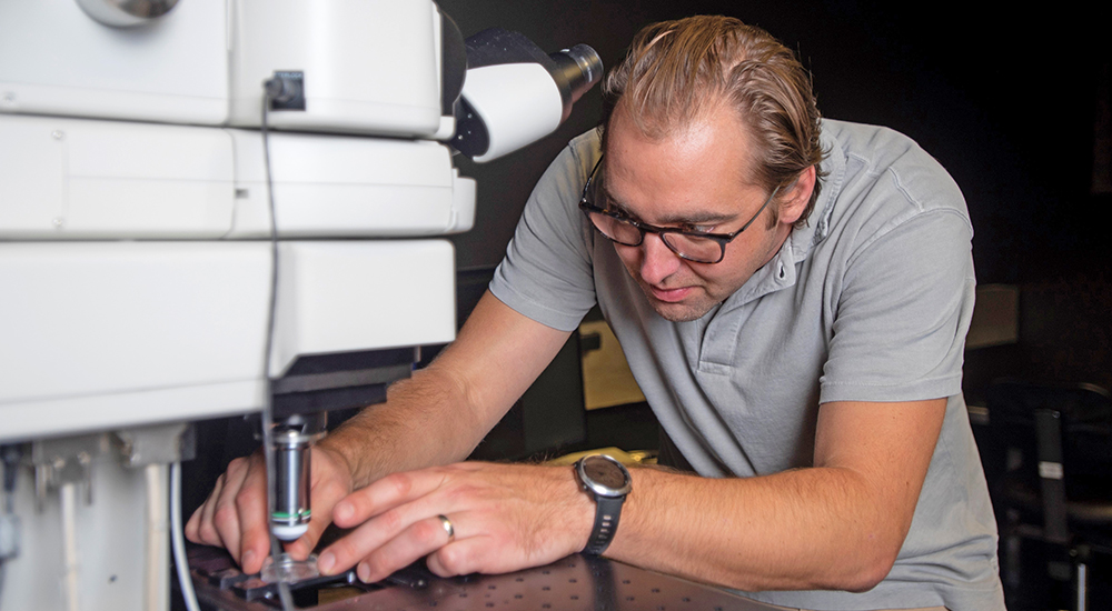 Technician places slide under microscopes