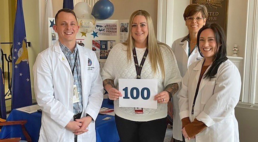 Veteran Jennifer Higginbotham and VA staff holding sign that says 100