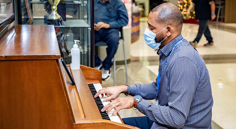 Man playing piano in hospital lobby