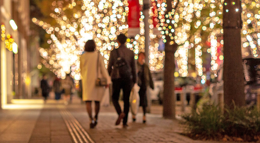 Couple walking under trees with holiday lights