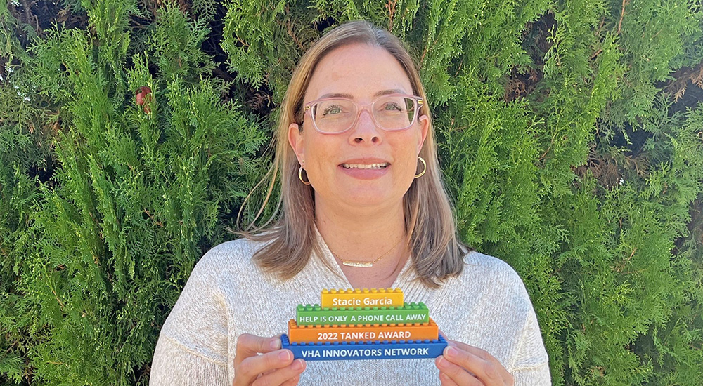 Female VA employee holding small signs; VA innovation revolutionaries