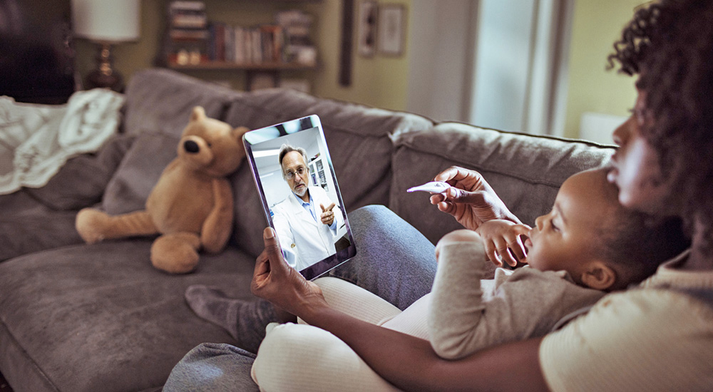 Woman with baby talking to doctor online; telehealth