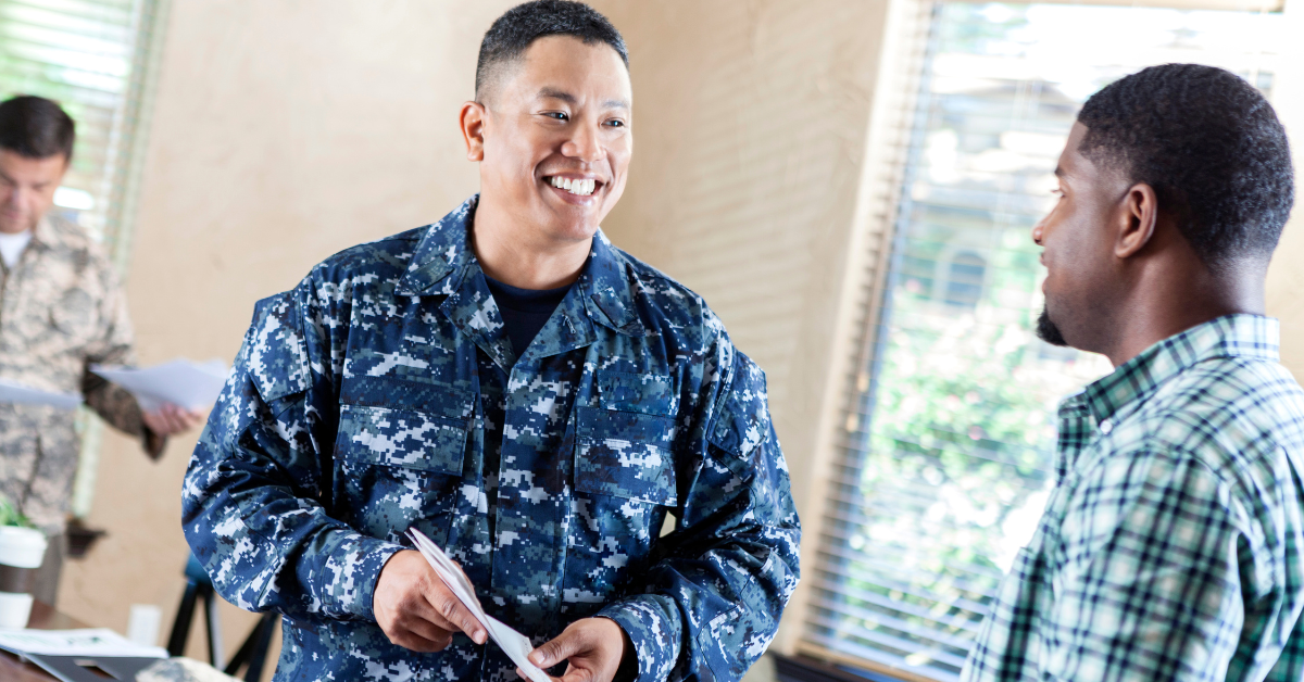 man in uniform smiling and talking to other man