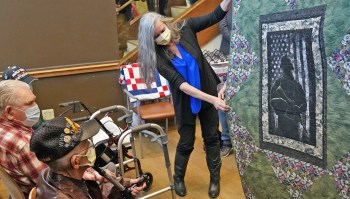 Woman shows Veteran a quilt