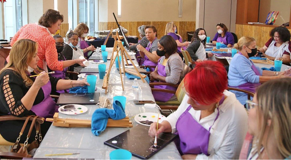 Large group of caregivers painting on canvas