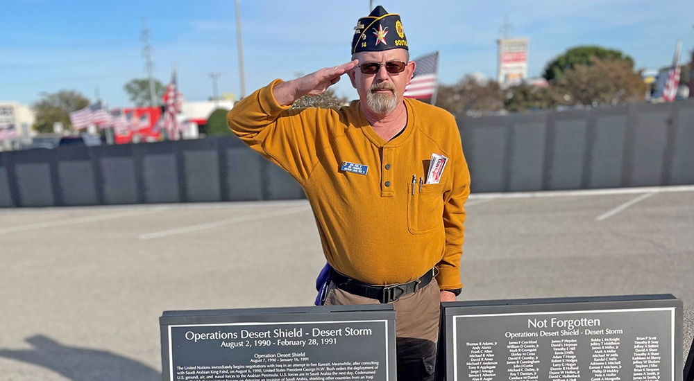 Veteran saluting in front of memorial signs; PTSD Coach