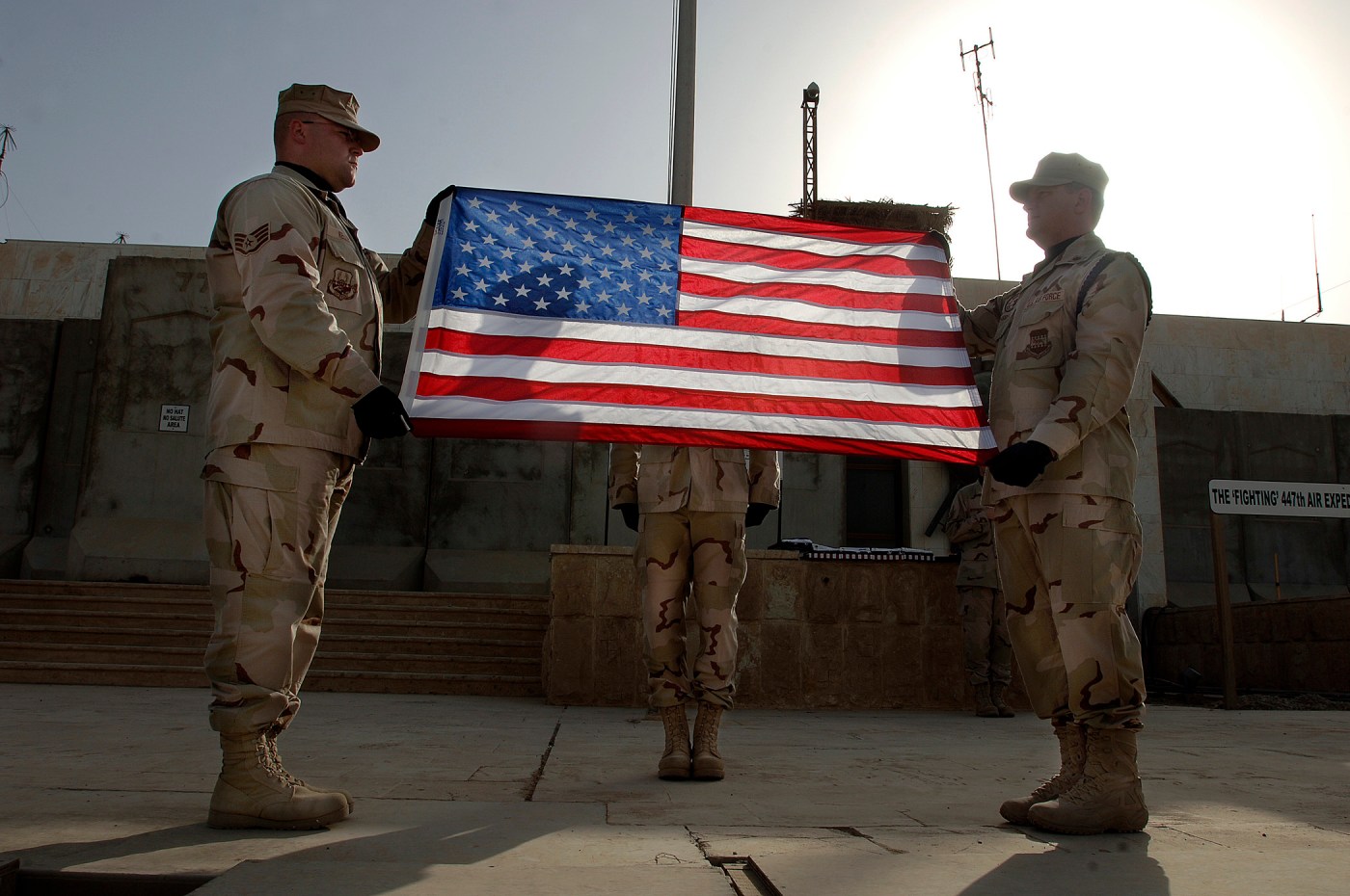 two men in uniform performing a flag folding ceremony
