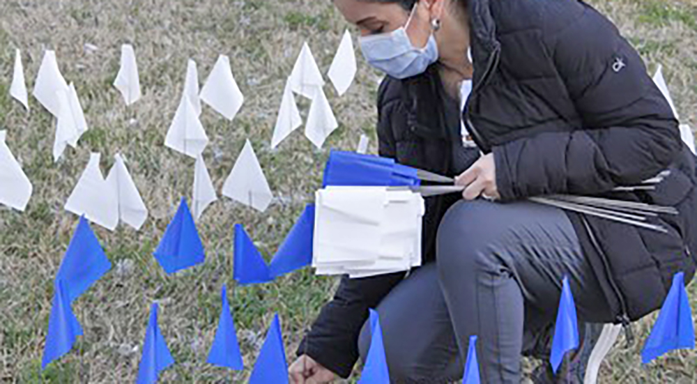 Woman placing flags in the ground; COVID-19 pandemic