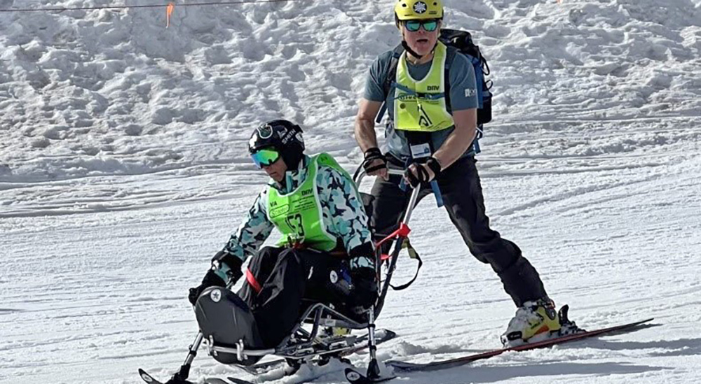 Man pushing man in ski sled; winter sports
