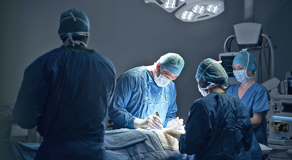 Doctors performing surgery in operating room; surgical smoke