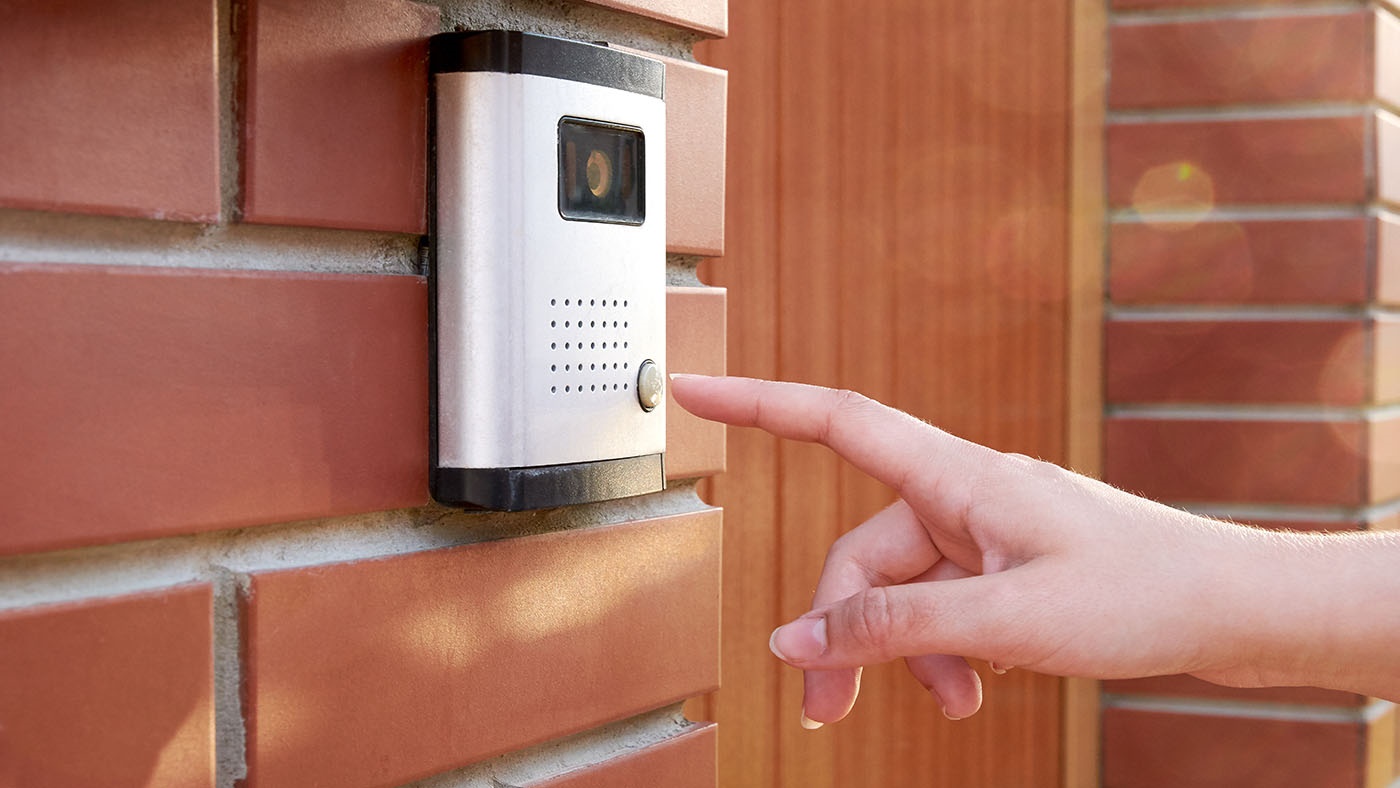 Hand ringing the doorbell on a smart device doorbell camera.