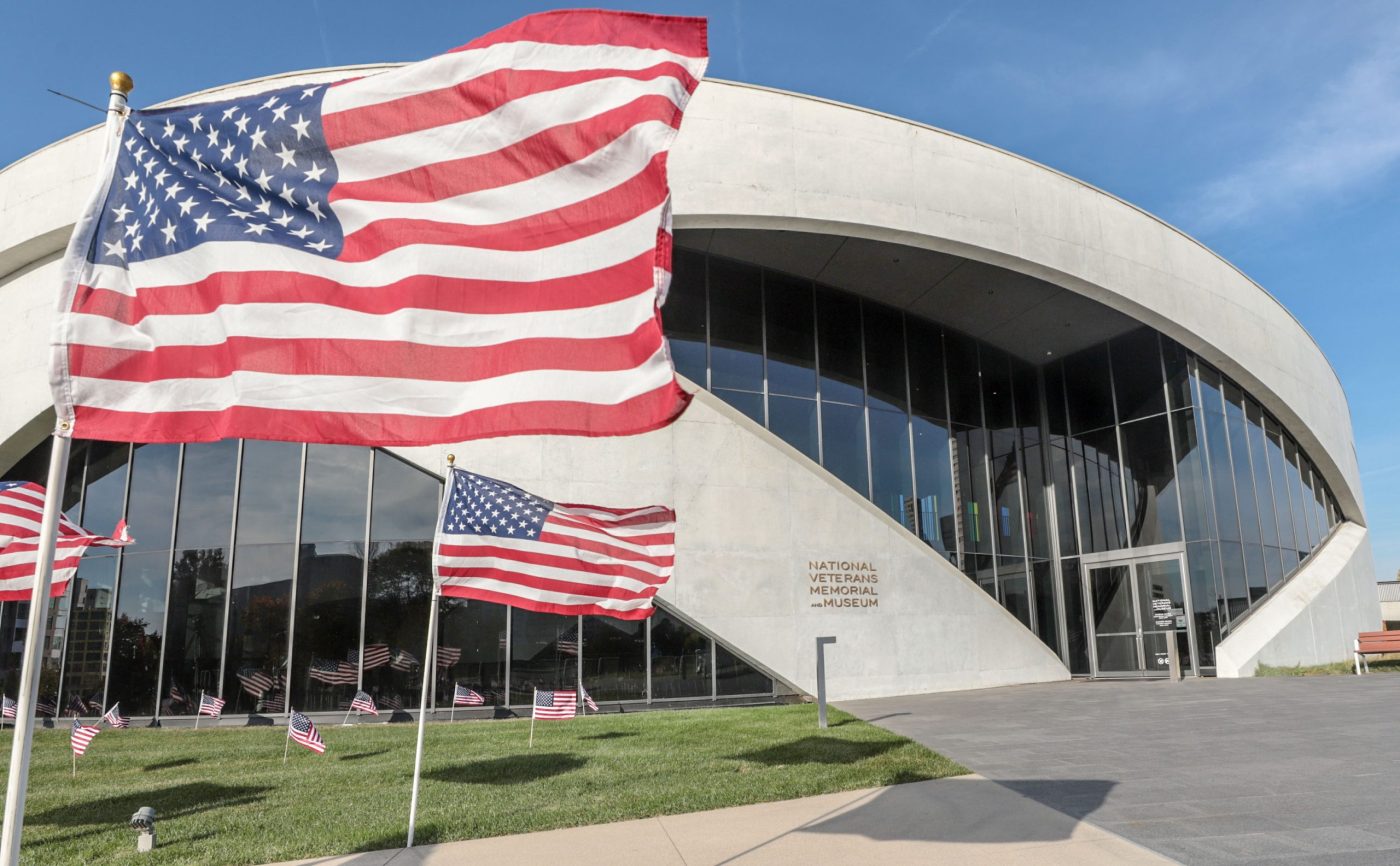American flags waving in the wind in front of the National Veterans Memorial and Museum.