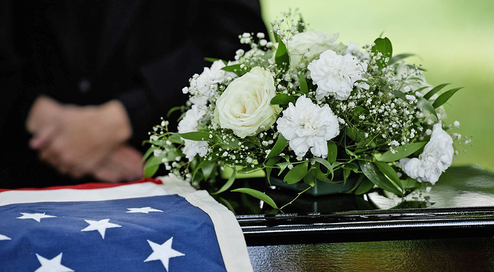 Wedding flowers and flag on casket