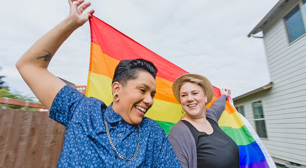 Two LGBTQ+ women with Pride flag