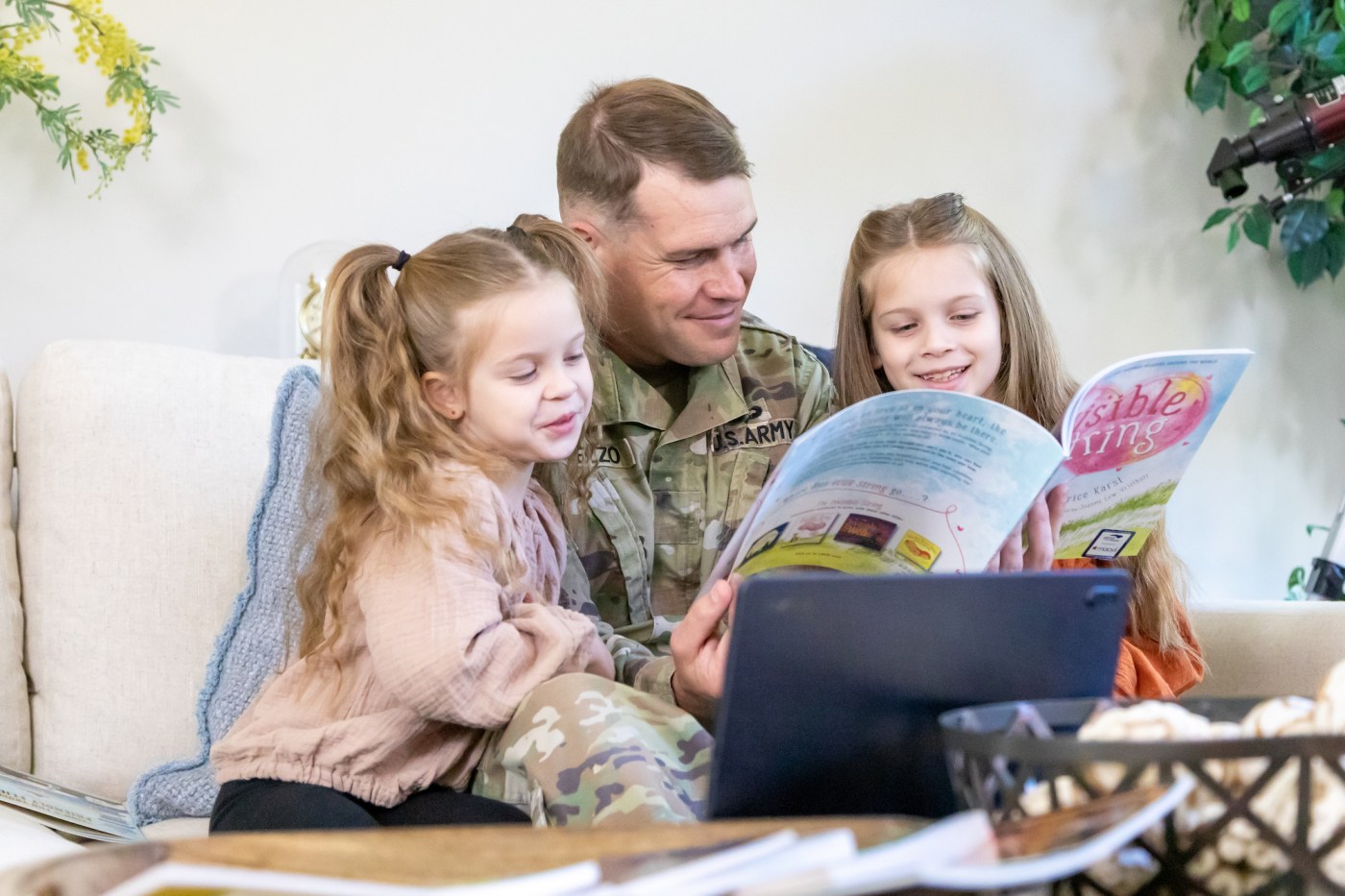 man in military uniform and two children reading book together as a family