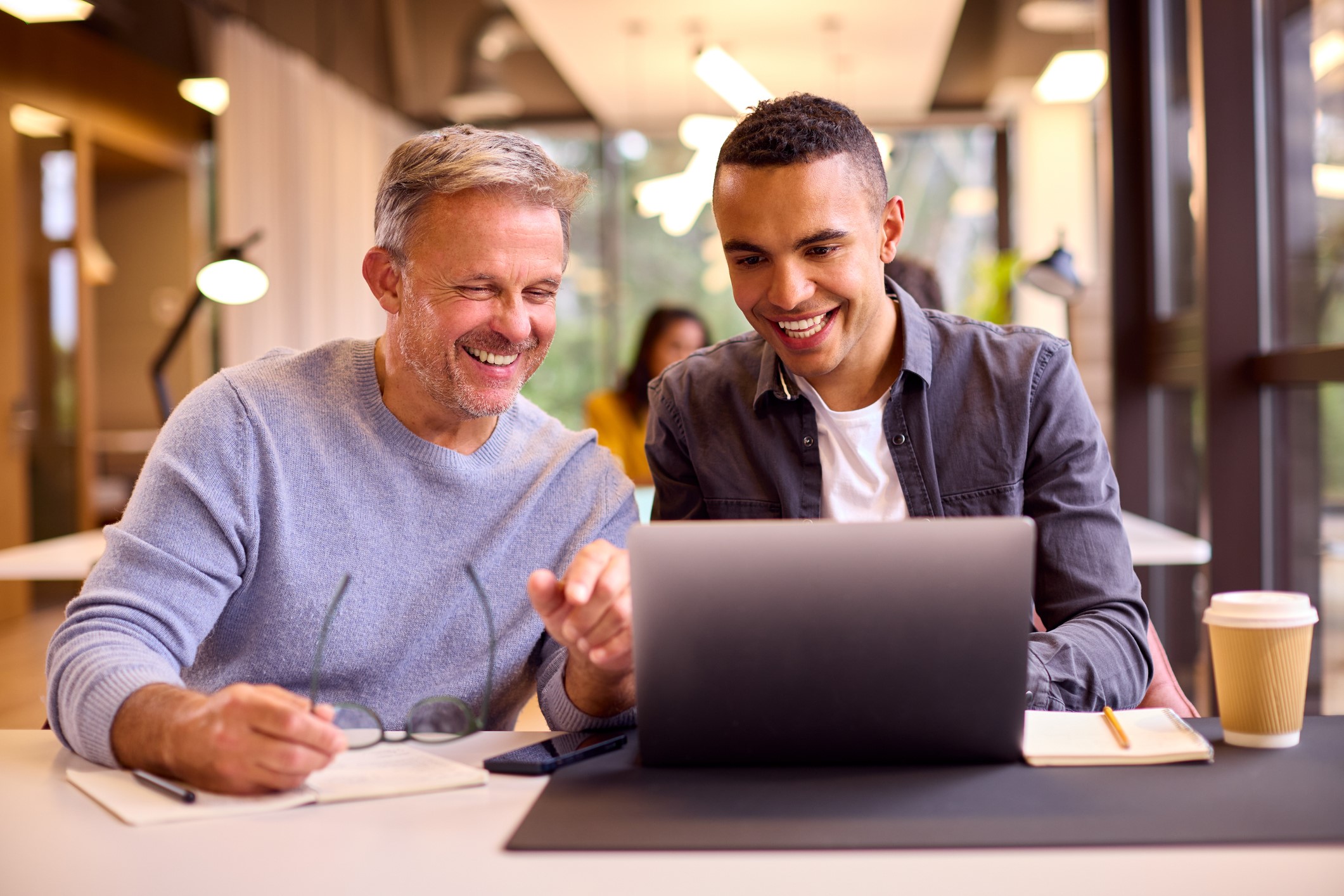 two men sitting at laptop one is mentoring the other with career guidance