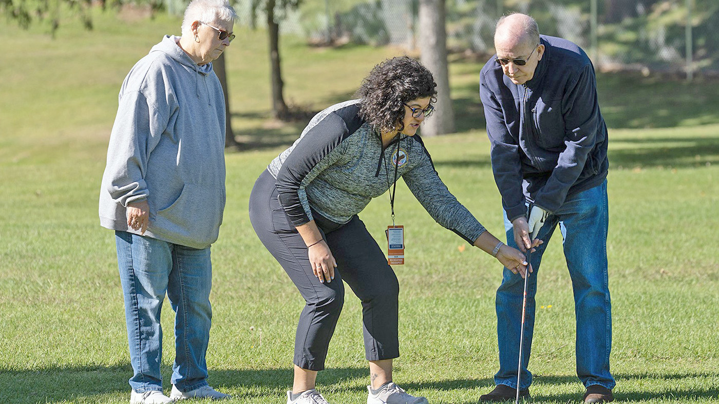 Woman assists Veteran in golf scramble