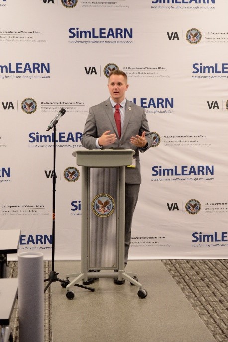 A man talking behind a podium at the SLICE & Simulation Showcase at SimLEARN.