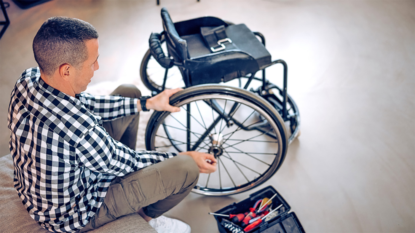 Pop Up Pit Stop man changing wheel on wheelchair