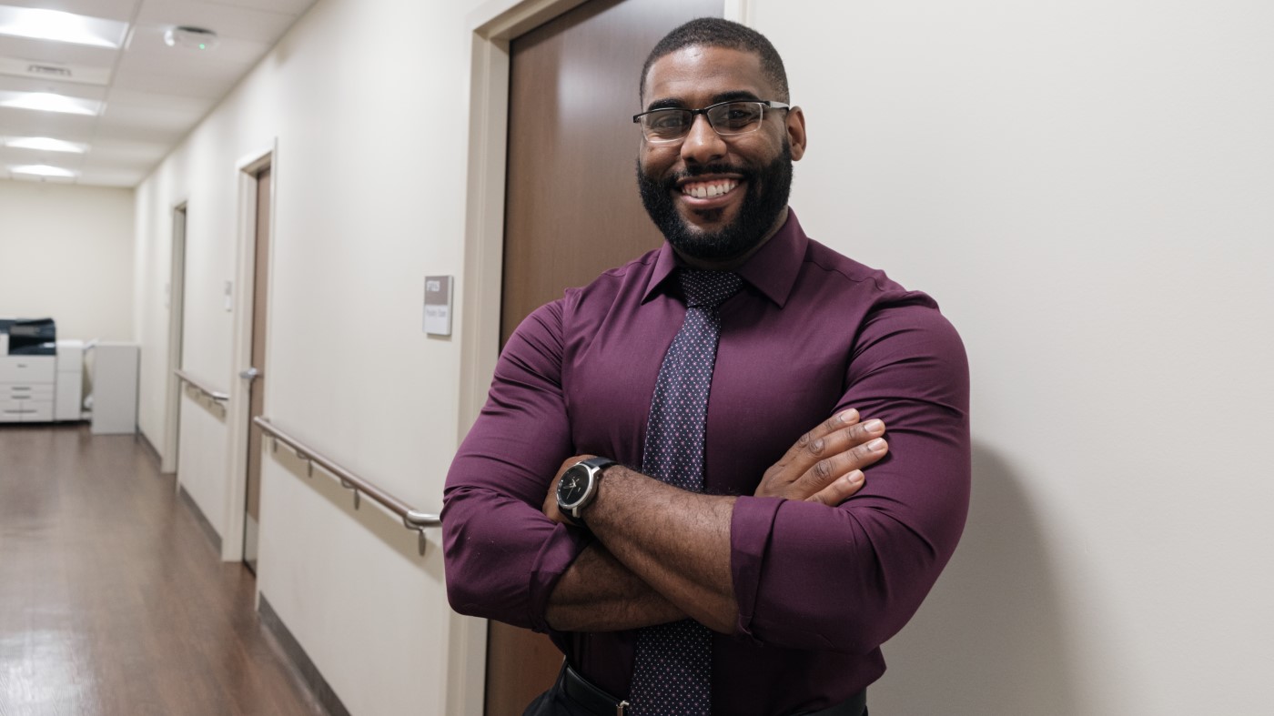 A man in a purple shirt in a hallway in a VA facility.