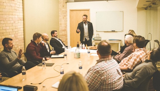 Man at front of boardroom table teaching a class for Warrior Rising