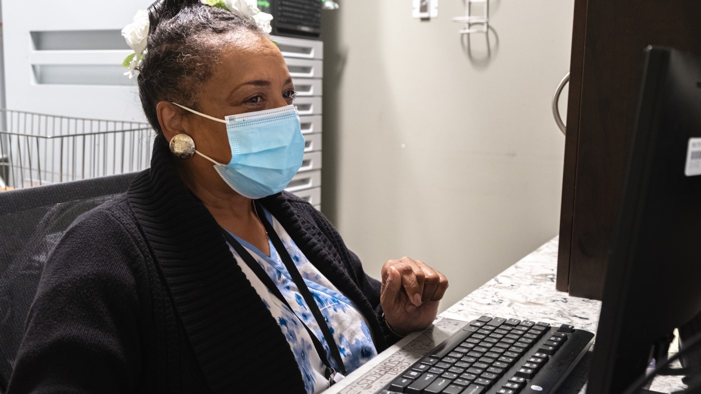 A woman in a mask conducting a job search at a computer.