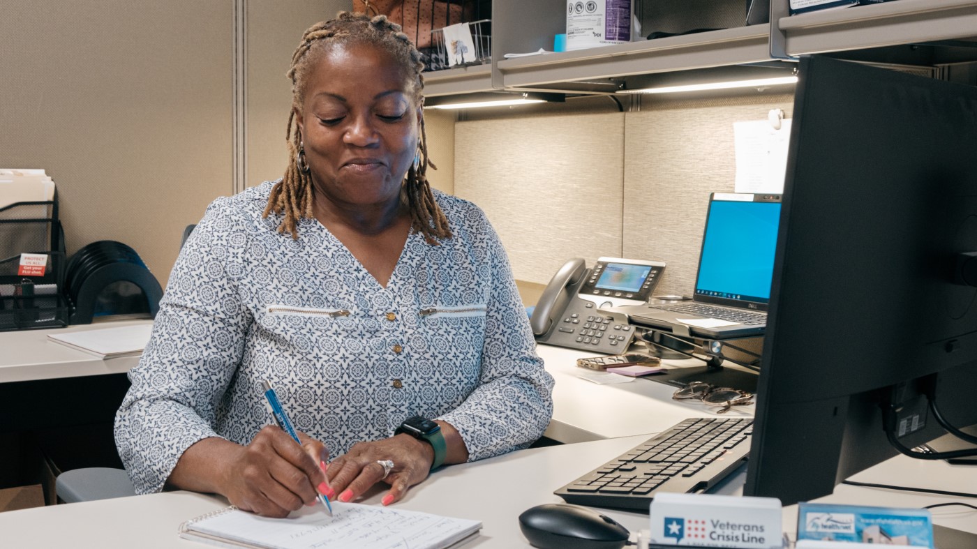 A contract specialist fills out paperwork at her desk.