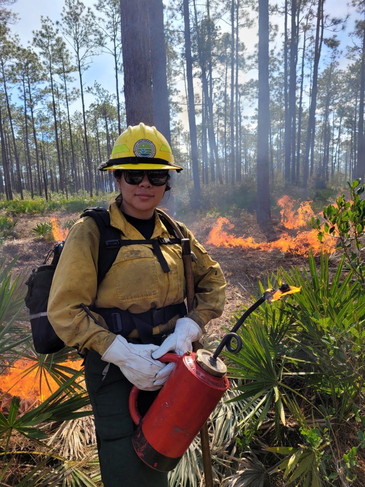 young woman dressed in fire safe gear working in forest
