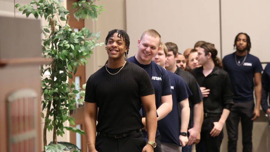 Men in line smiling graduating from defense manufacturing program.