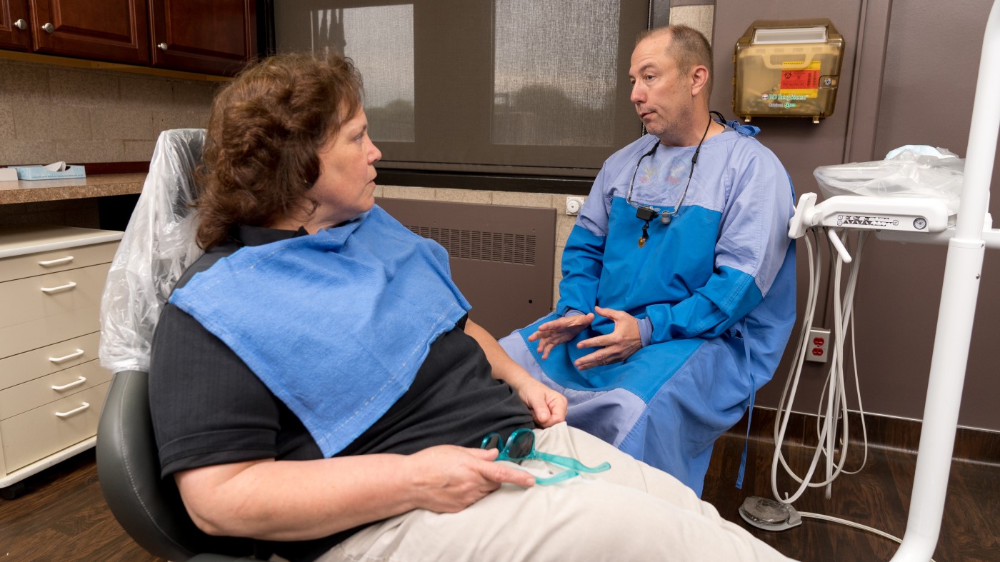 A VA dentist explains a procedure to a Veteran patient.
