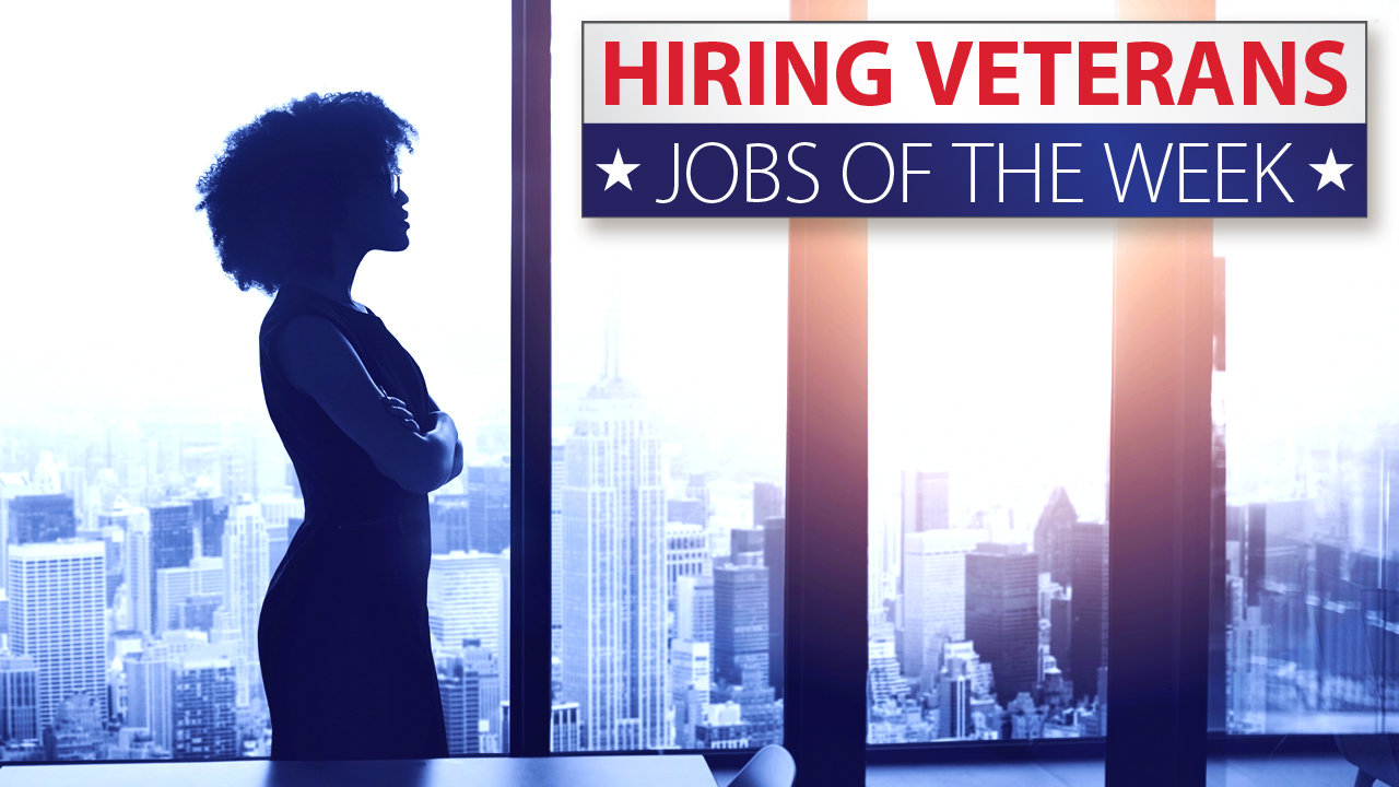 Hiring Veterans. Jobs of the week. Woman standing in front of windows looking out of a high rise building.